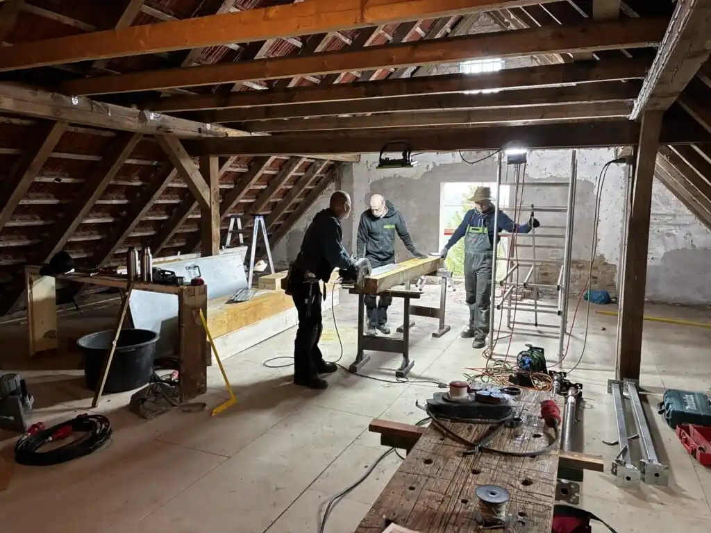 Drei Arbeiter beim ausbau des Dachstuhls